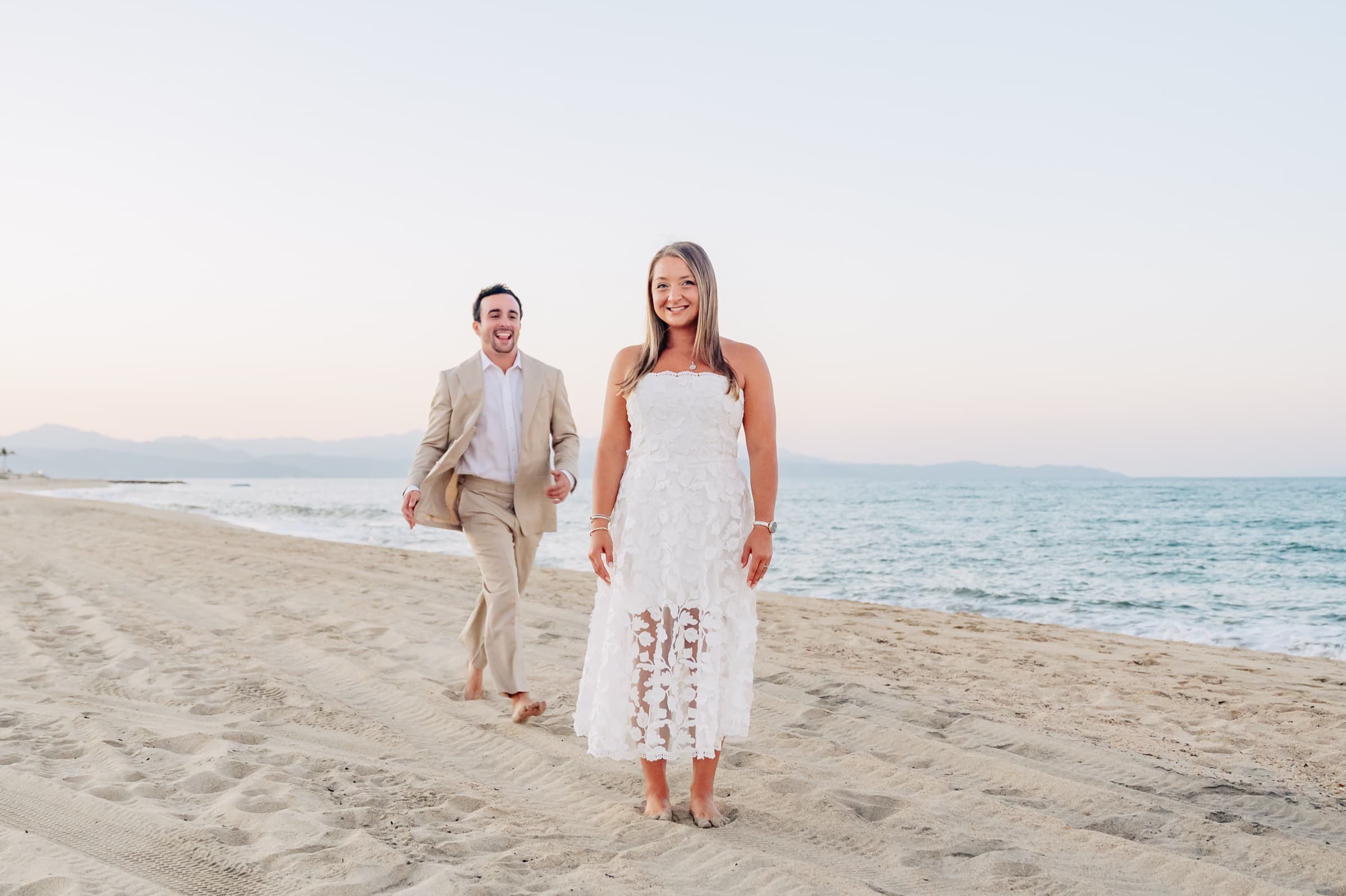 Walking together on the beach smiling at the camera