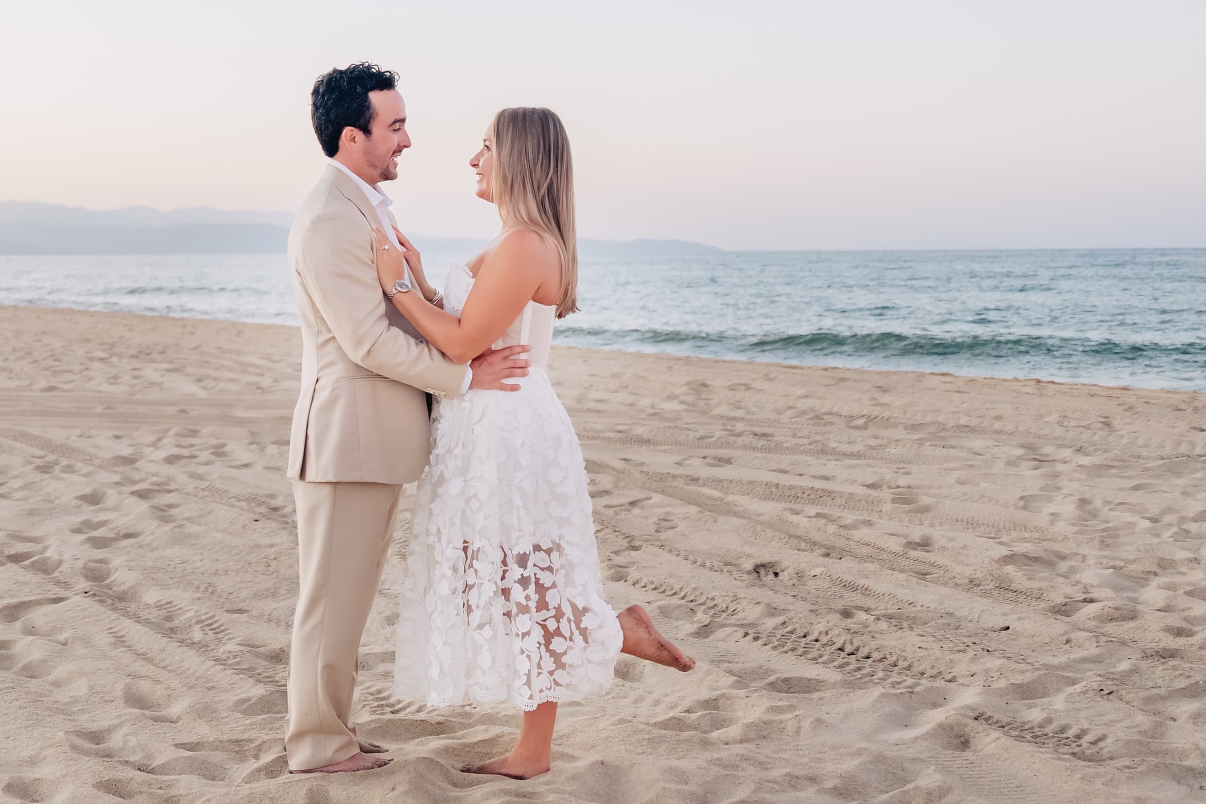 Embracing on the beach with ocean waves at dusk
