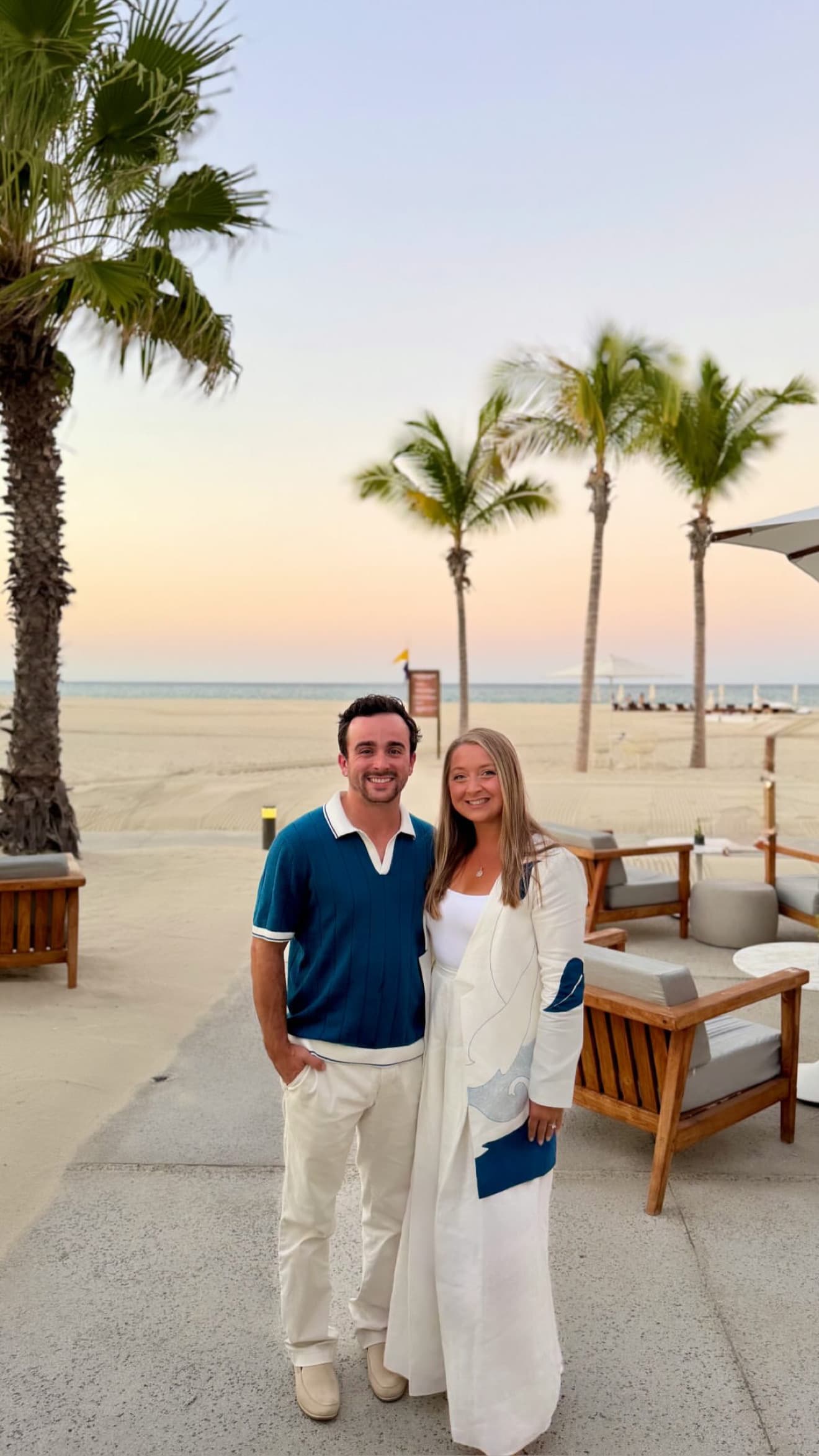 Couple at a beachfront restaurant with palm trees at sunset