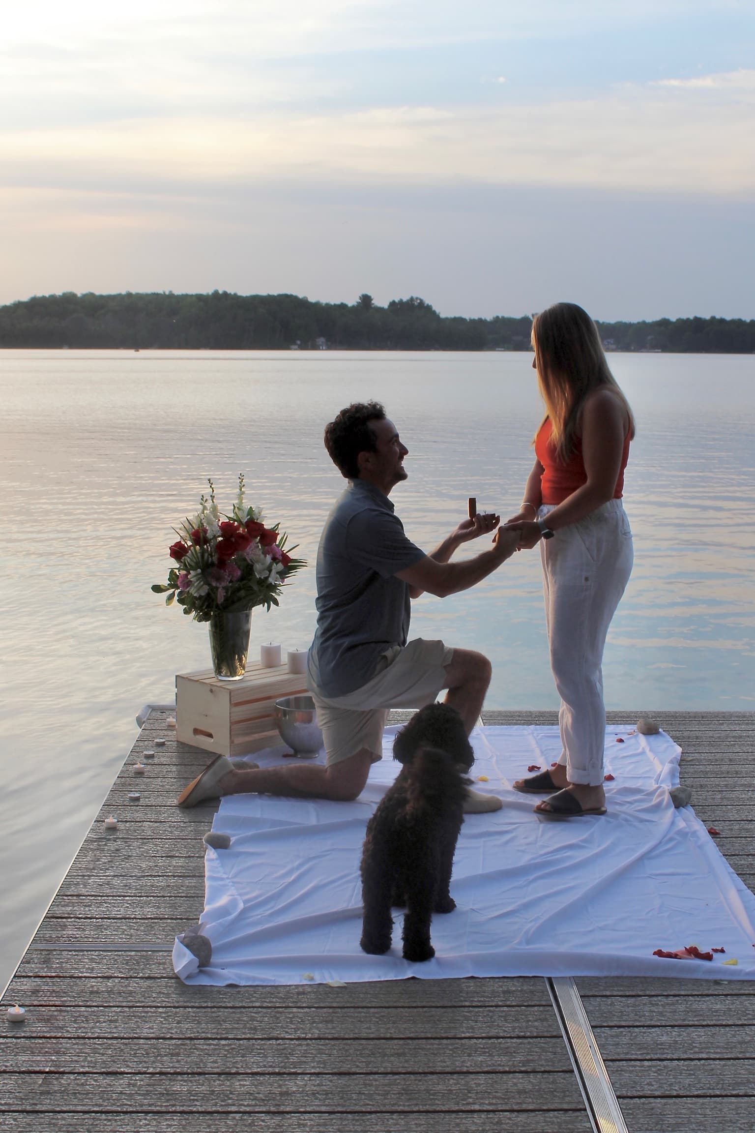 Jeffrey proposing on a dock at sunset with their dog
