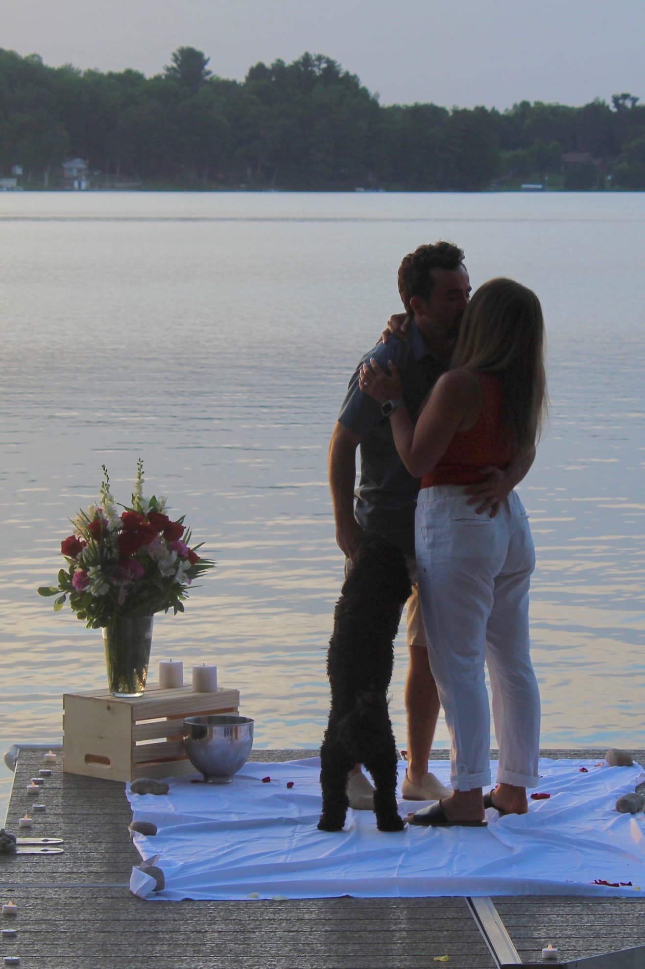 Embracing on the dock after the proposal with their dog