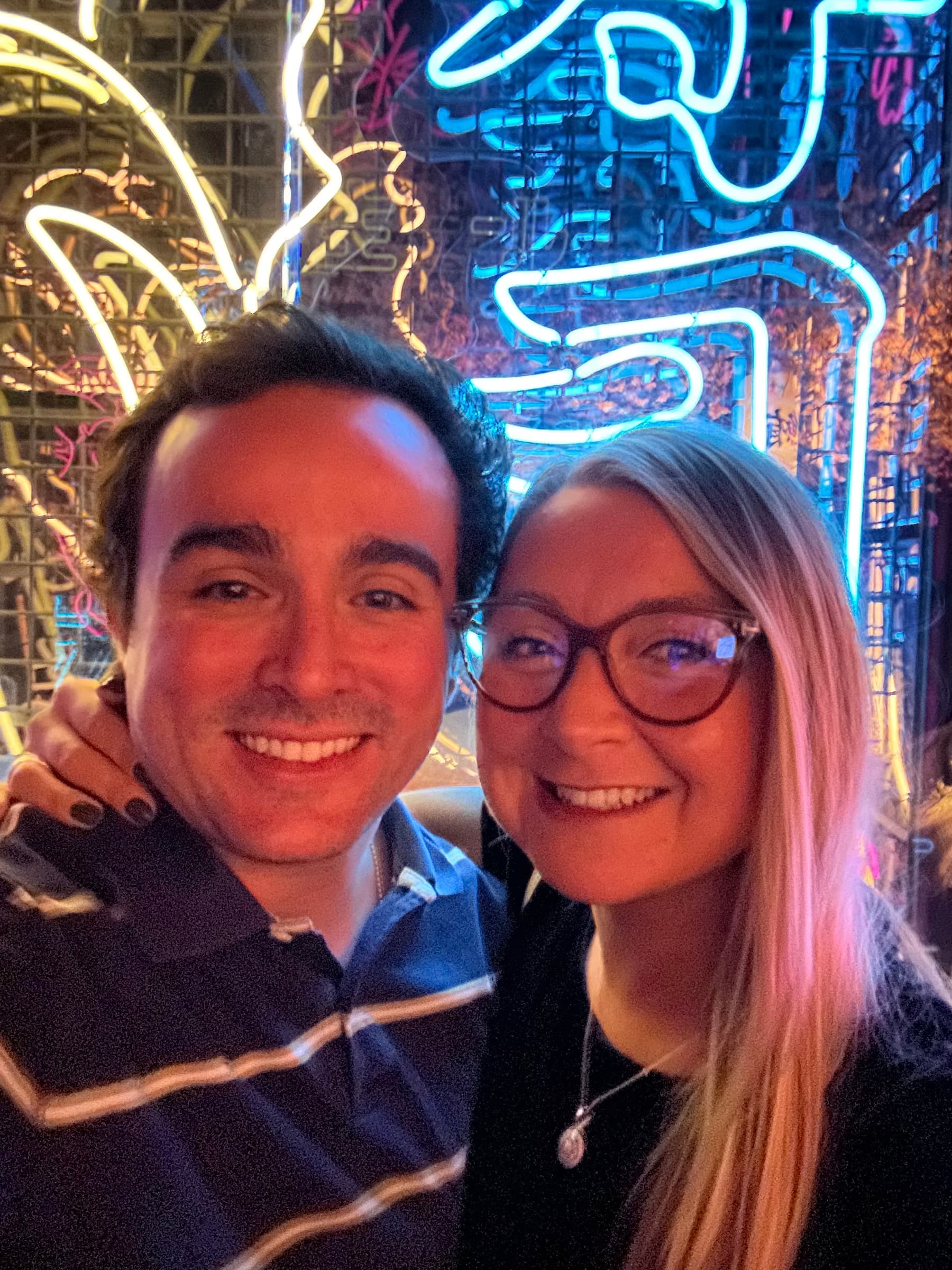 Smiling selfie in front of neon signs at night