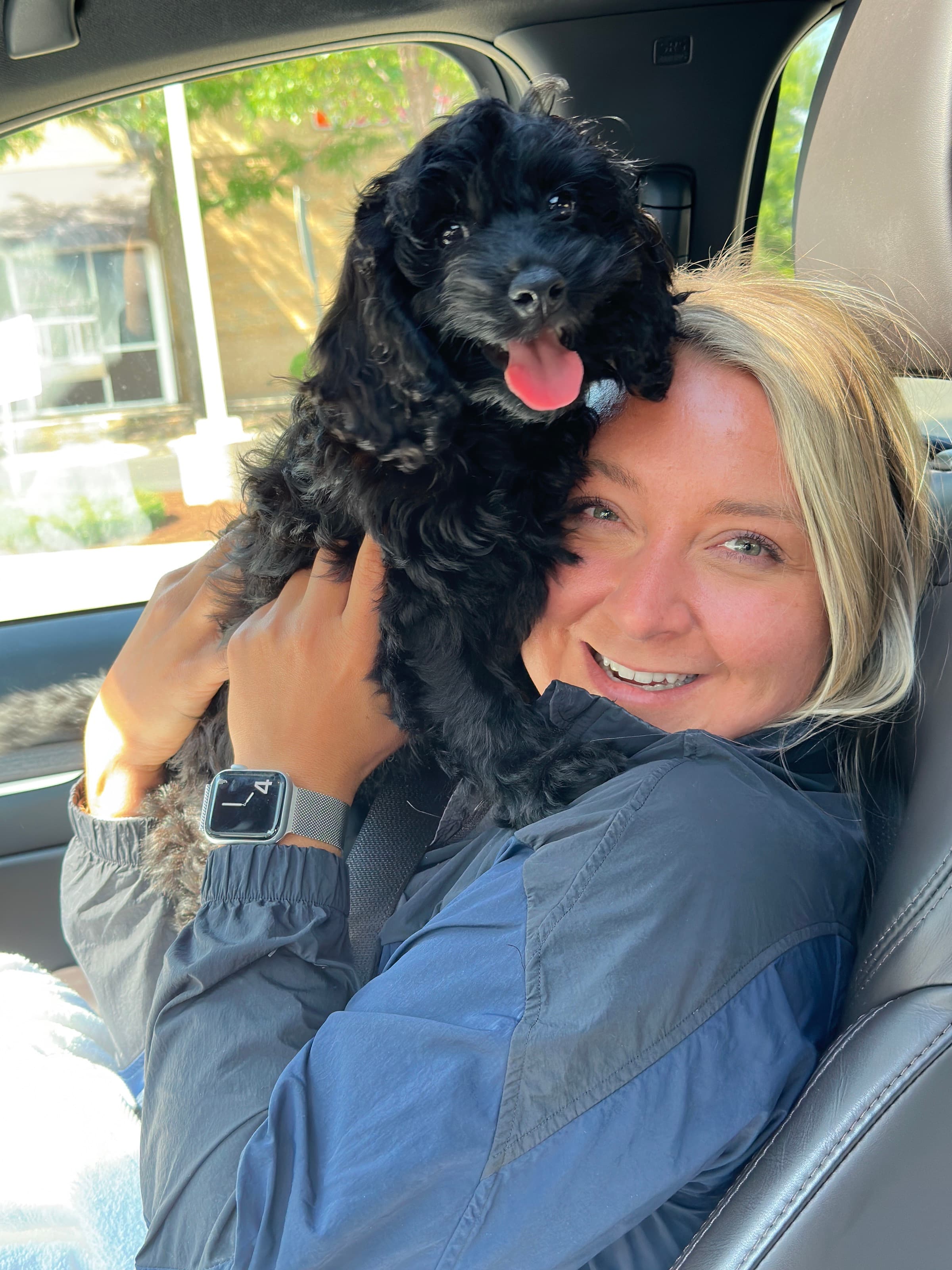 Taylor holding their black puppy in the car