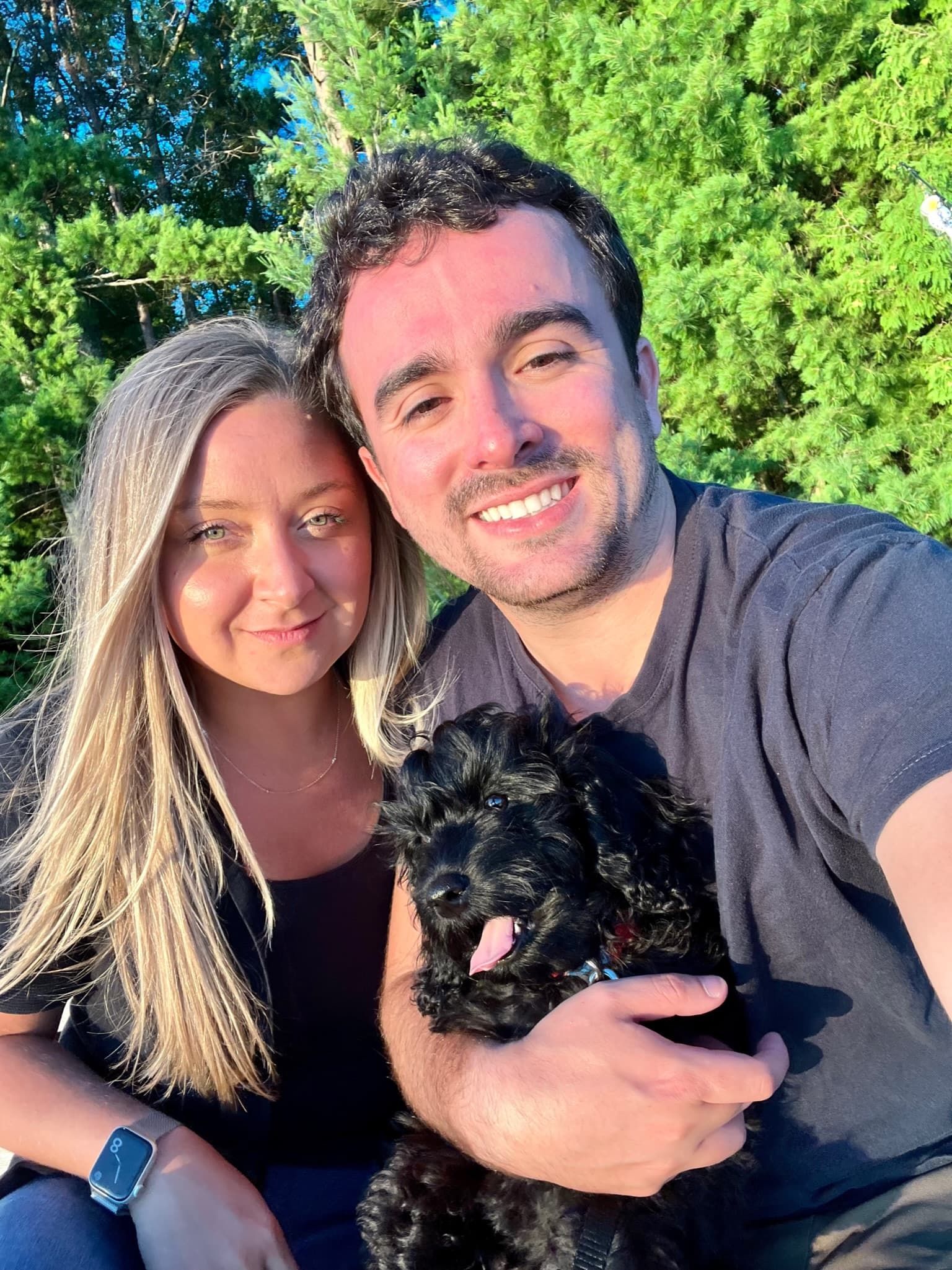 Selfie with their black puppy in the park