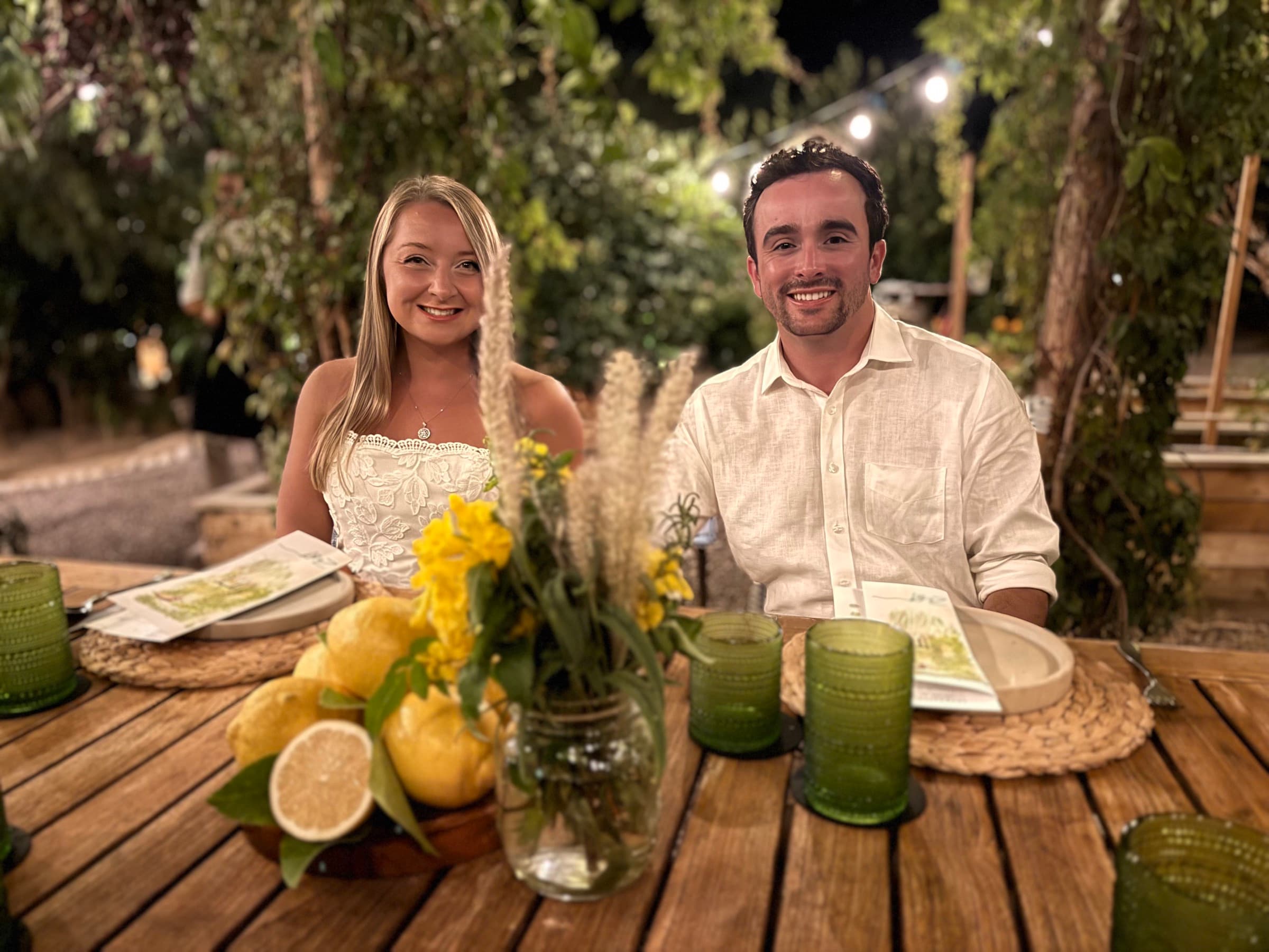 Seated at an outdoor dinner table with lemons and candles