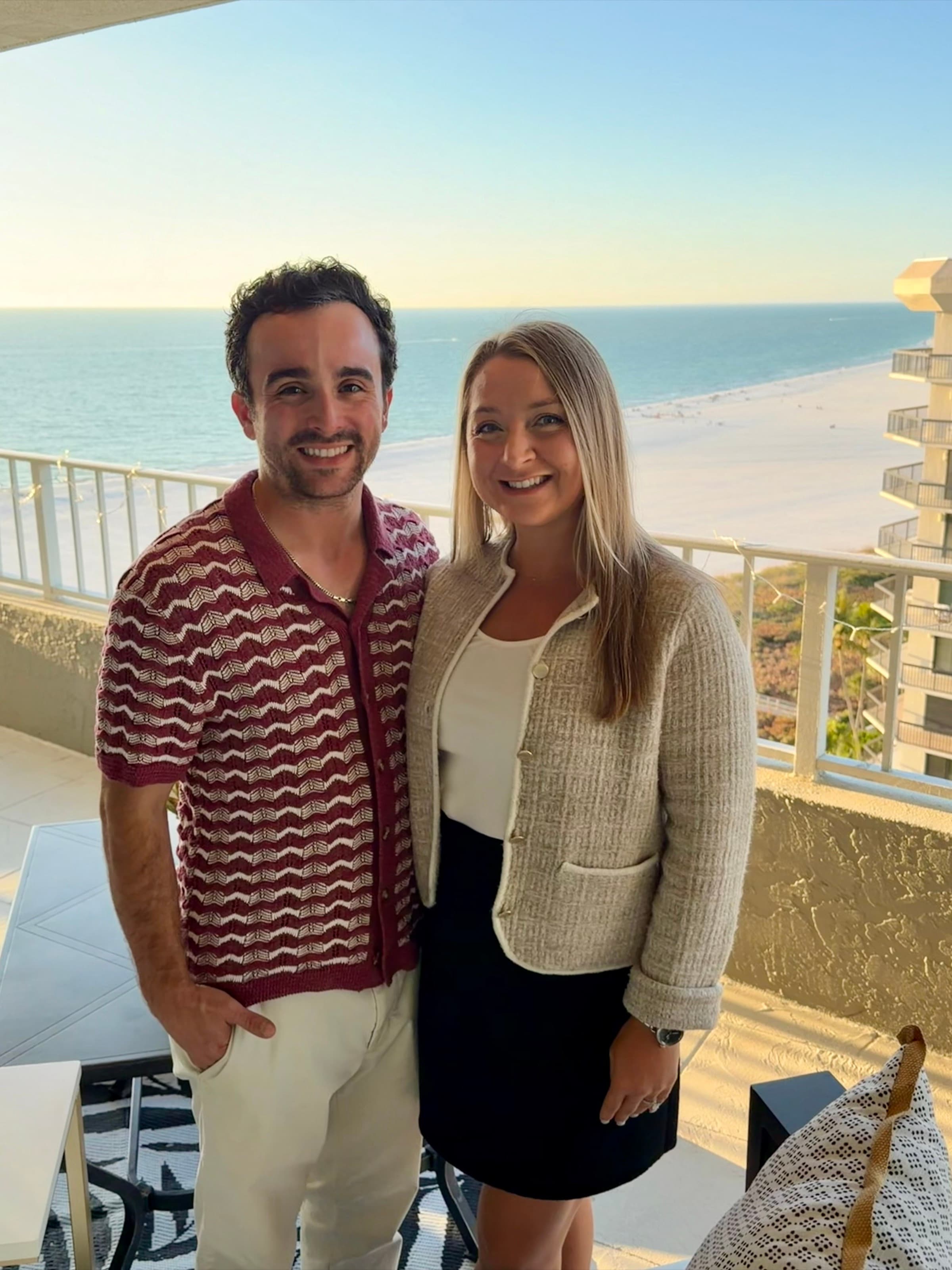 Smiling on a high-rise balcony overlooking the beach