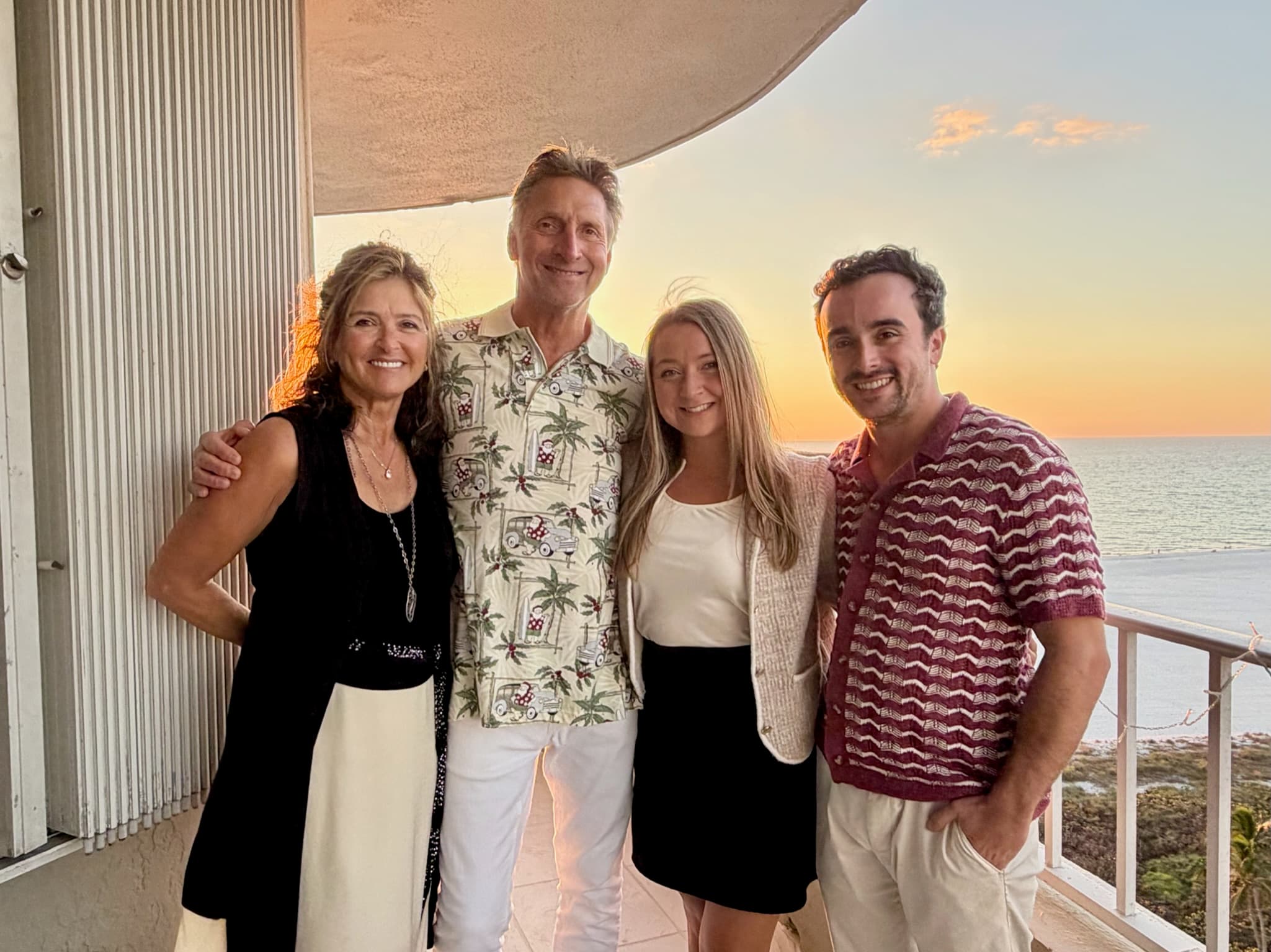 Family photo on a balcony with an ocean sunset behind