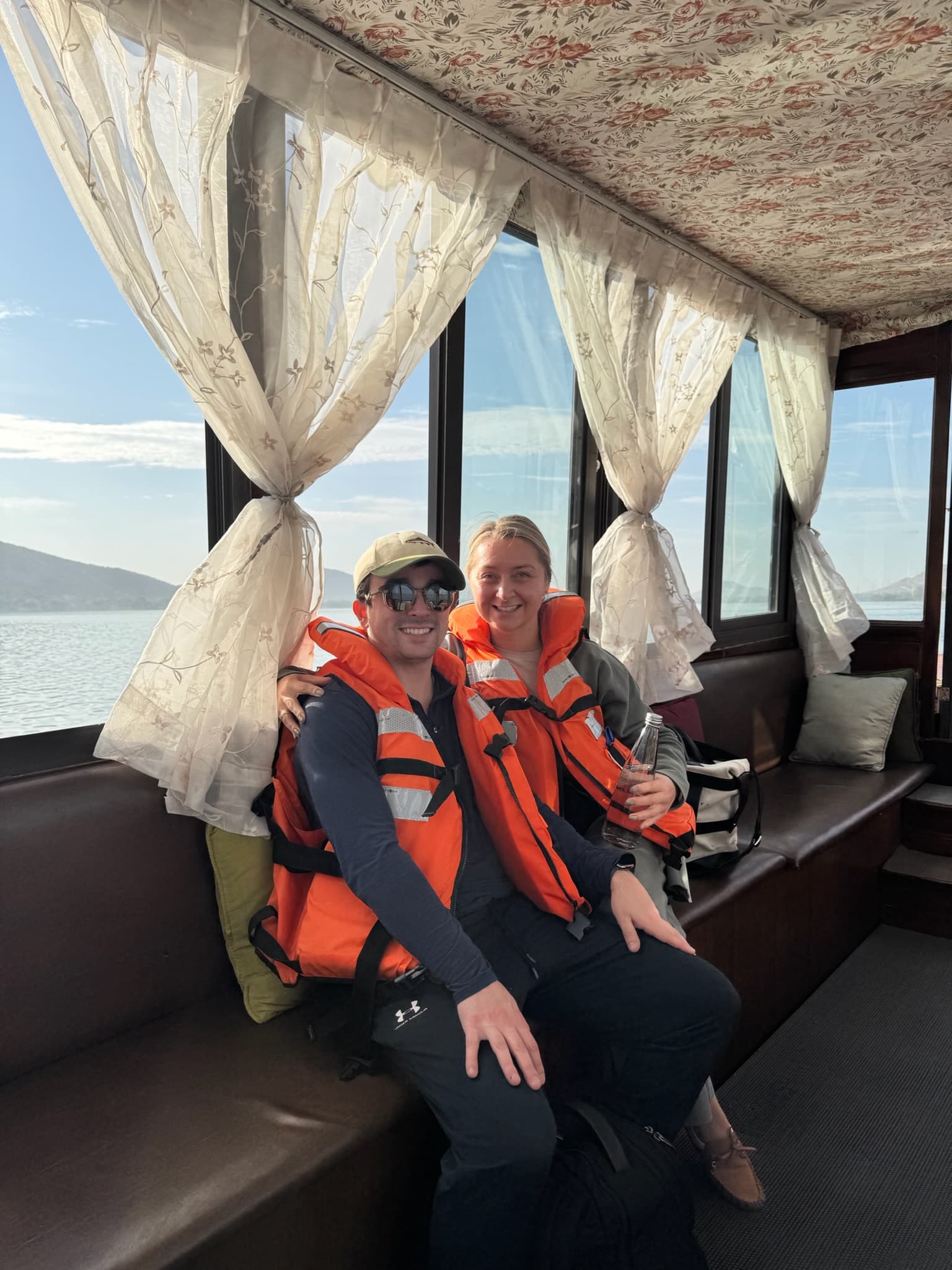 Wearing life jackets on a boat with mountain lake views