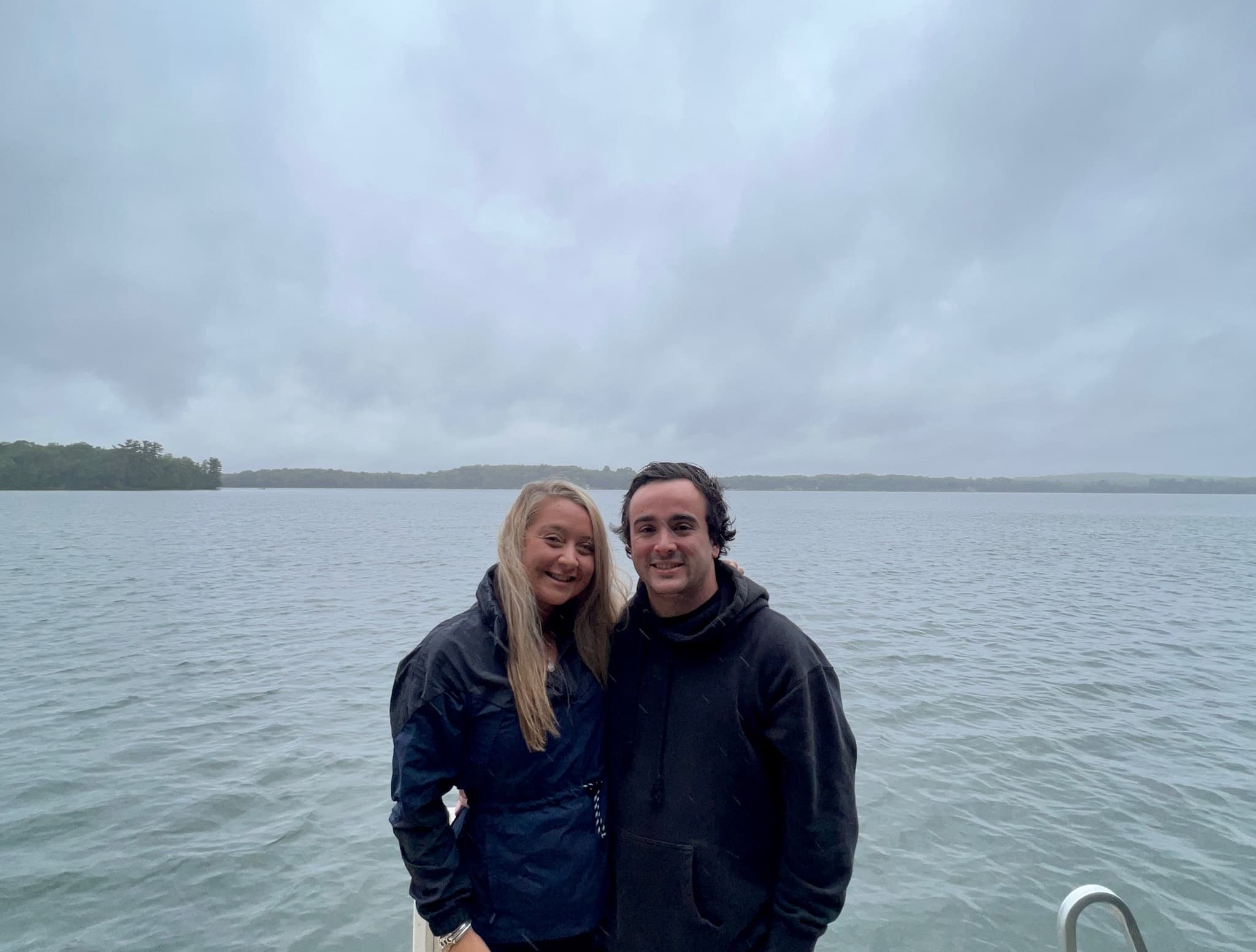 Smiling together on a boat on a cloudy lake day